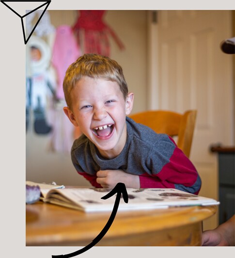 Child reading and laughing over a lesson book